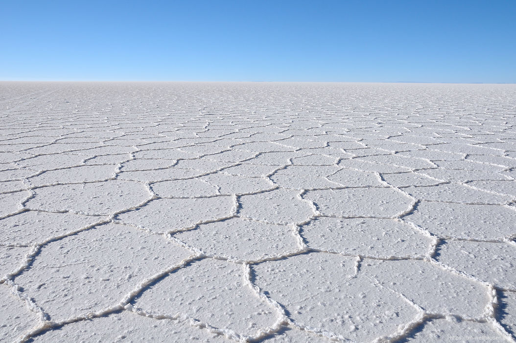 Bilder aus Bolivien - Die Salzkruste des Salar de Uyuni bricht in hexagonalen Formen auf und zieht sich bis zum Horizont hin.