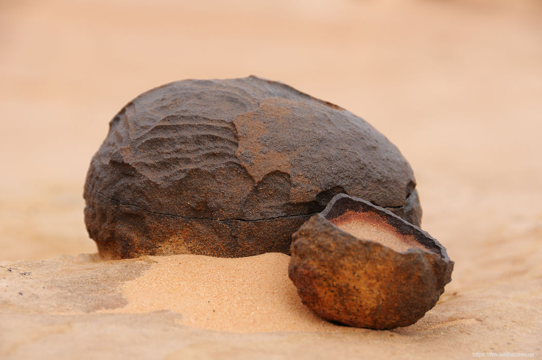 Moqui-Kugeln bestehen aus einer dünnen Eisenwand und sind im Inneren mit Sandstein gefüllt. Vielerorts liegen sie auf dem Boden oder sind noch im Stein eingewachsen, teilweise schon aufgeknackt.